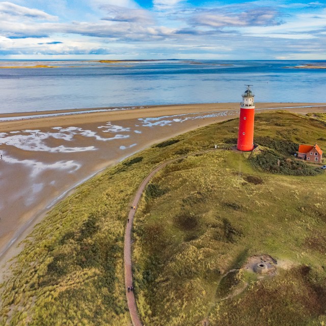 Lighthouse at the Wadden island Texel in the dunes during a calm autumn afternoon with reflections on the North Sea beach. The Eierland lighthouse is located at the North point of the island.